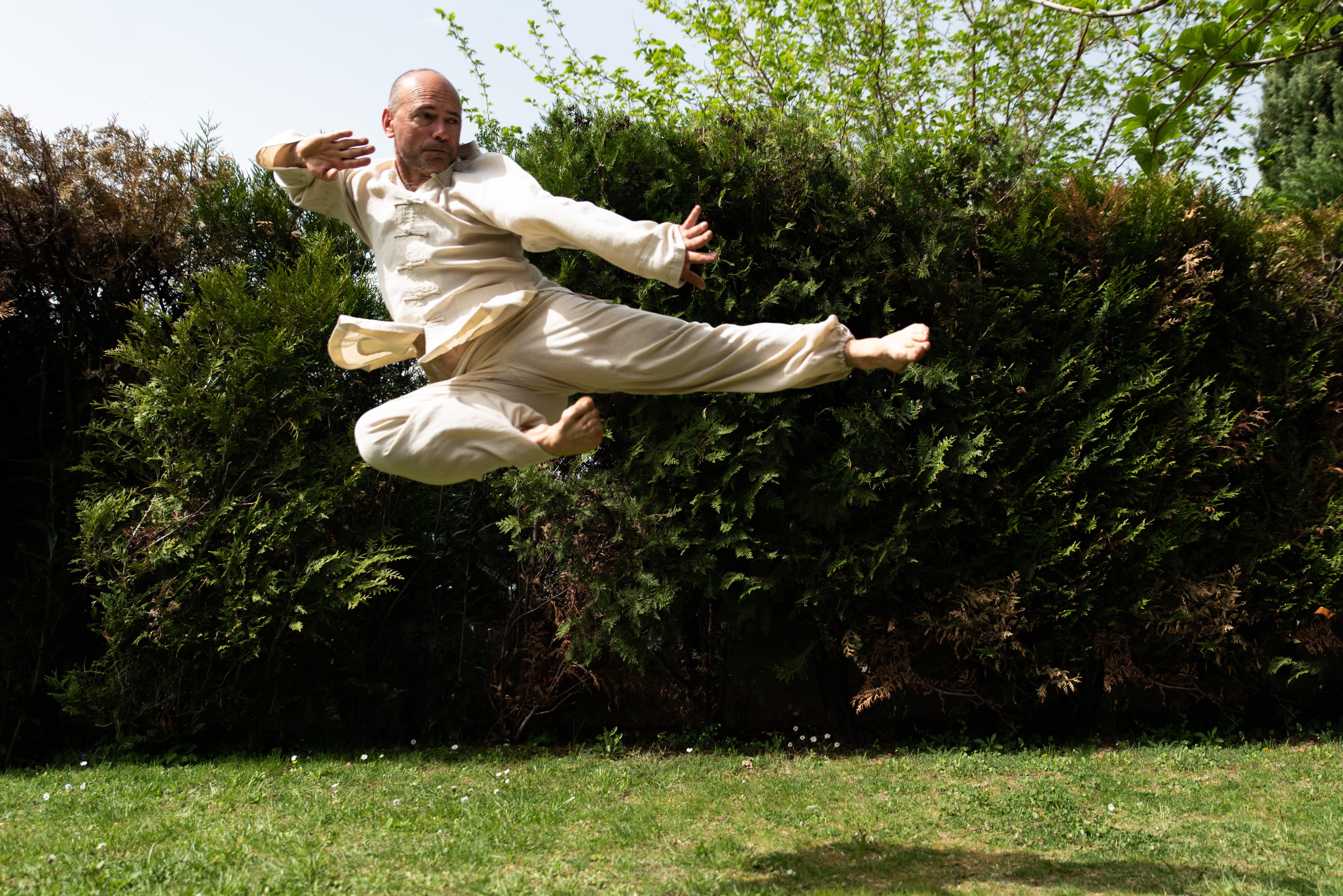 Didier Turc en coup de pied sauté, tenue de kung-fu claire
